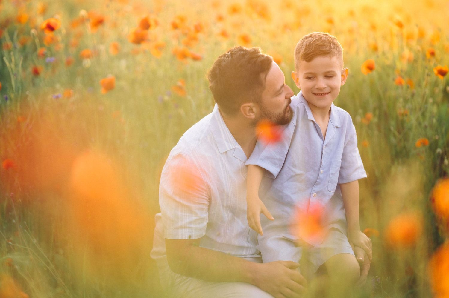 Orange poppies bloom in a sunlit meadow as two figures share a joyful moment among the wildflowers at sunset.