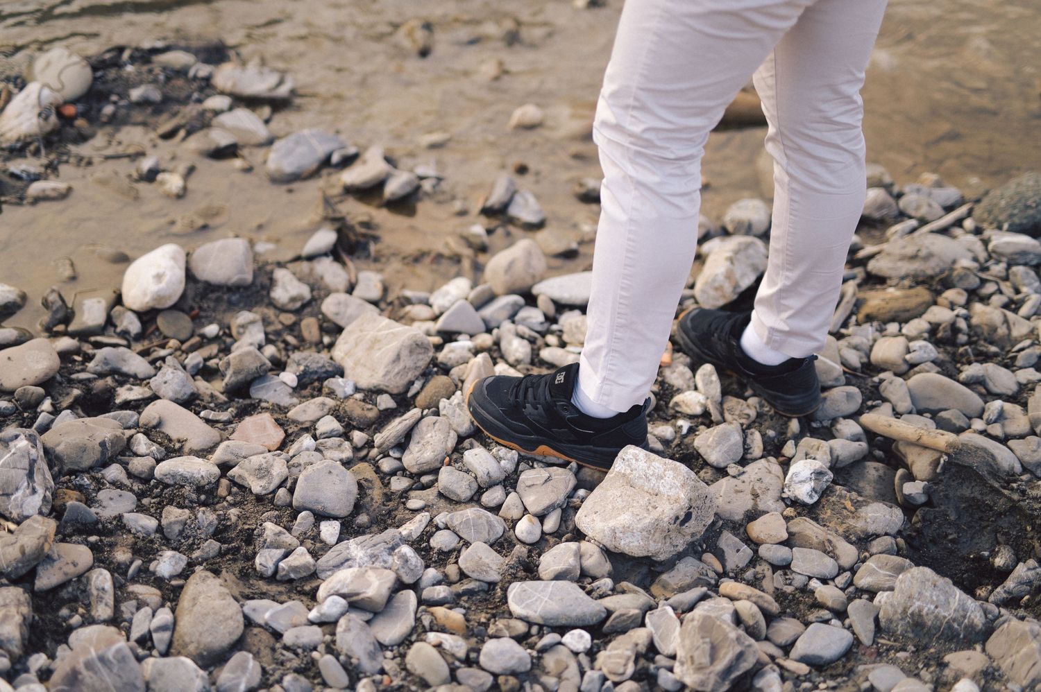 Medical personnel in protective gear walks carefully across rocky terrain while conducting field work.