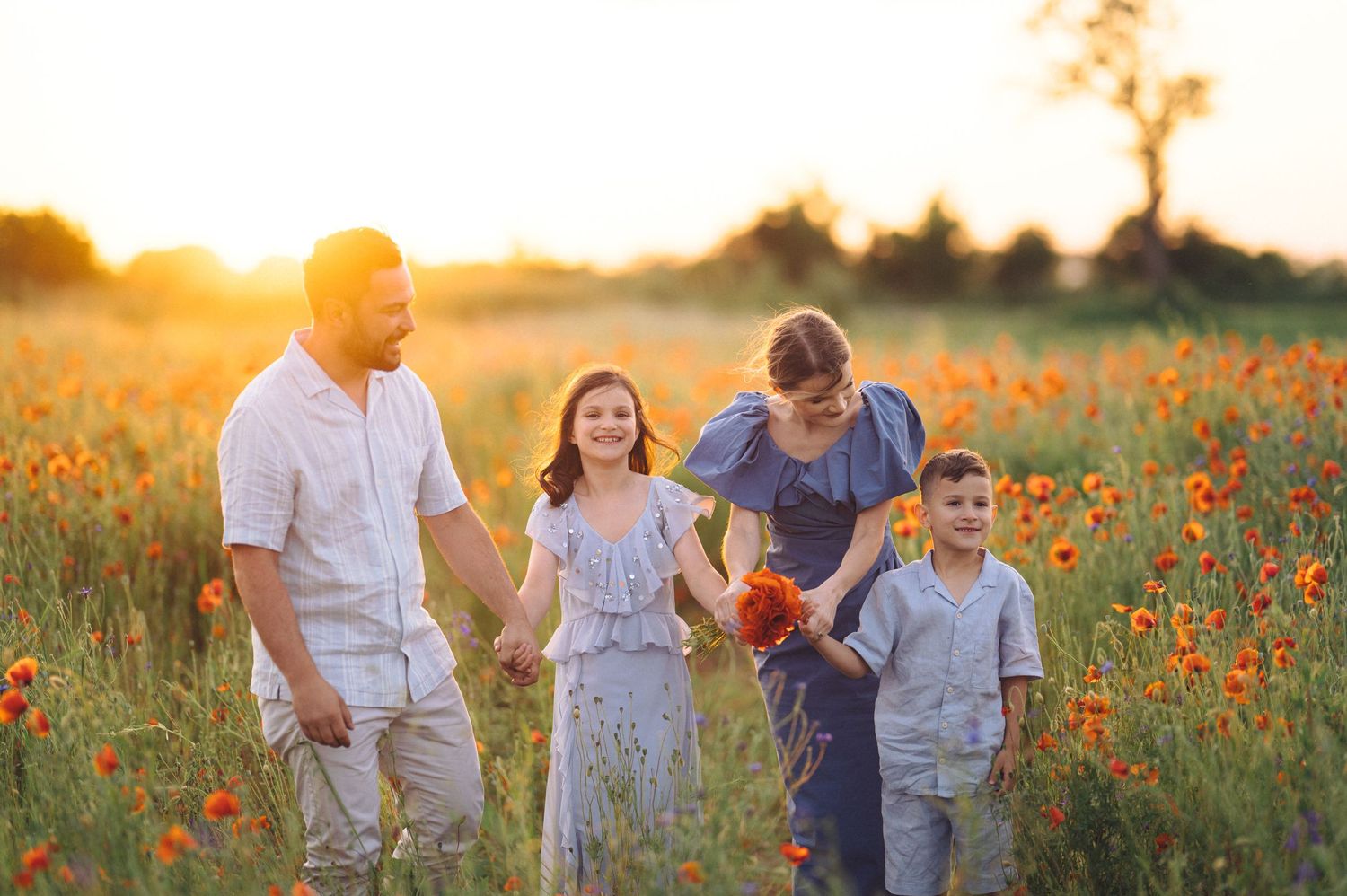 Family walks together through a vibrant wildflower field at golden sunset creating a heartwarming outdoor portrait.
