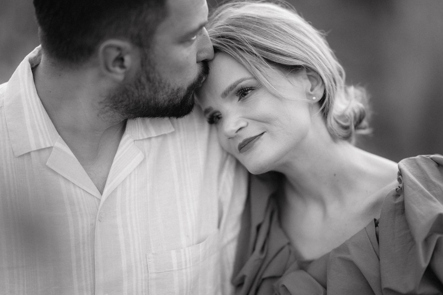 Black and white close-up of an intimate moment between a couple sharing a tender embrace outdoors.