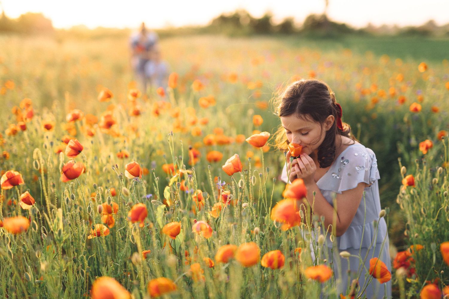 Children playing in a vibrant field of orange poppies during golden hour.