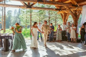 Guests dancing at a rustic wooden pavilion during a forest wedding celebration.