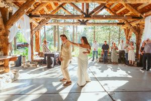 Natural light streams into a rustic wooden pavilion during a wedding celebration.