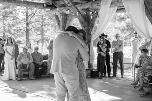 Black and white photo captures a couple's intimate dance moment under a covered outdoor pavilion.