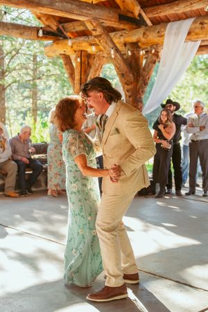Wedding dance taking place under timber frame structure with natural lighting.