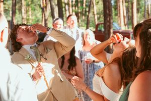 Wedding guests take shots at an outdoor celebration in the forest.