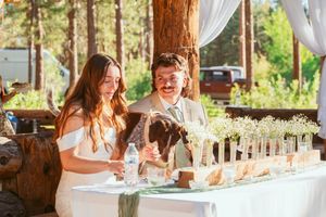 A couple shares a joyful moment together at their rustic outdoor wedding reception table.