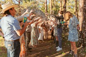 A celebratory moment in a wooded outdoor setting with guests spraying bubbles or confetti.