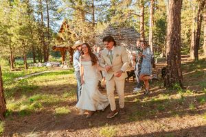 Guests walking down a forest path after an outdoor rustic wedding ceremony in a pine grove.