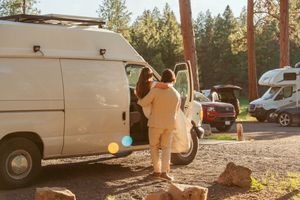 White vans parked in a rustic outdoor setting with pine trees and natural lighting.