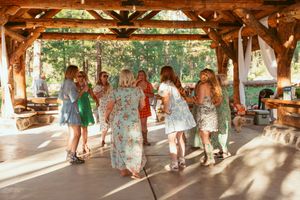 People dancing together on a covered wooden pavilion deck with natural forest scenery in the background.
