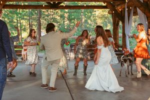 People dancing together under a wooden pavilion decorated with string lights.