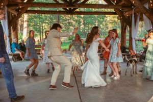 Couples dancing and celebrating at a rustic outdoor wedding reception.