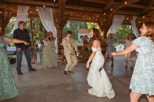 Wedding celebration under a wooden pavilion with fairy lights and white drapes.