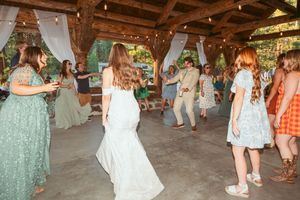 People dancing together on a rustic wooden dance floor at an indoor wedding celebration.