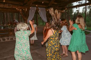 Wedding guests dancing together on the dance floor under string lights at an outdoor venue.