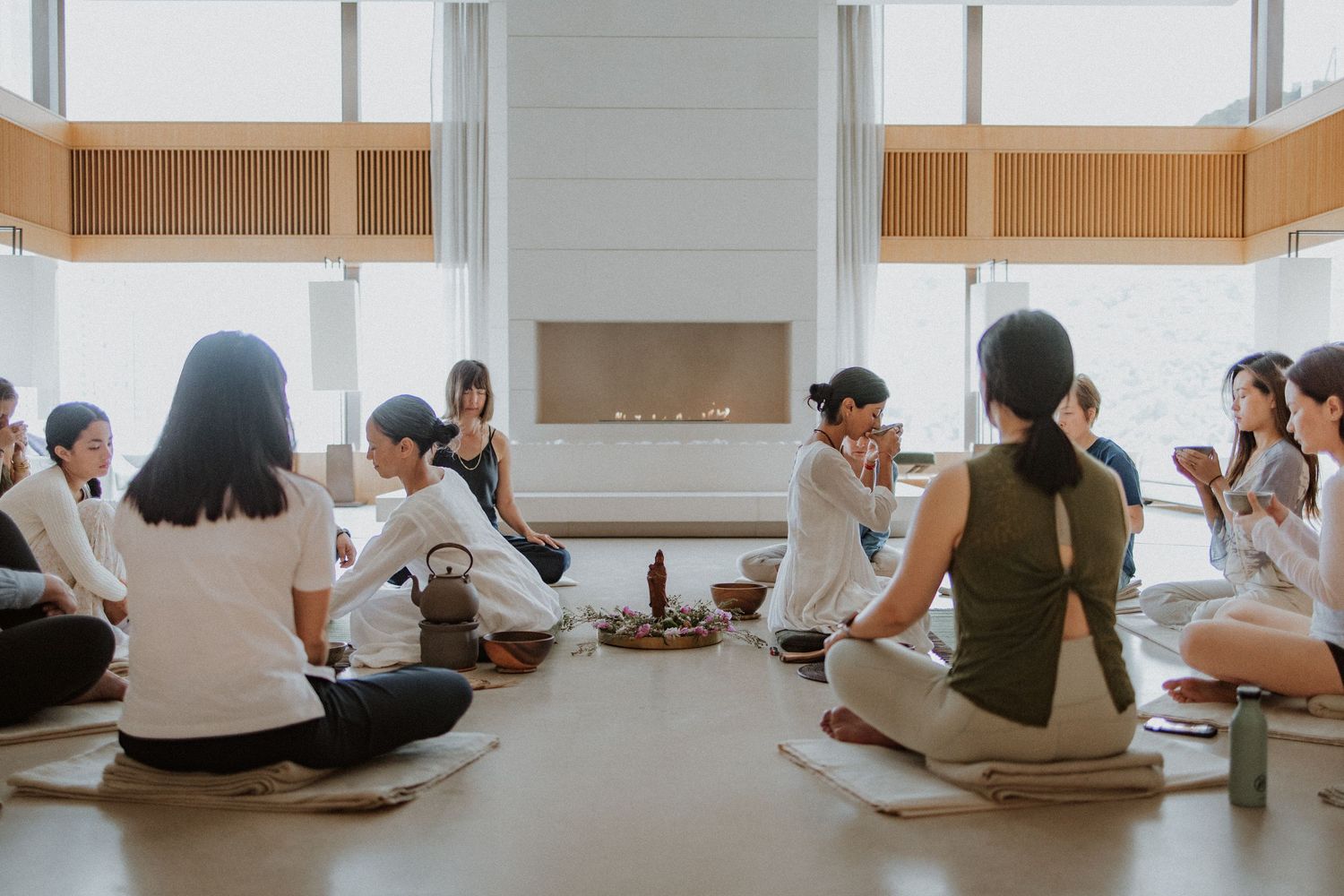 Group of students sitting in a circle on the floor during a casual social gathering in a bright modern room.