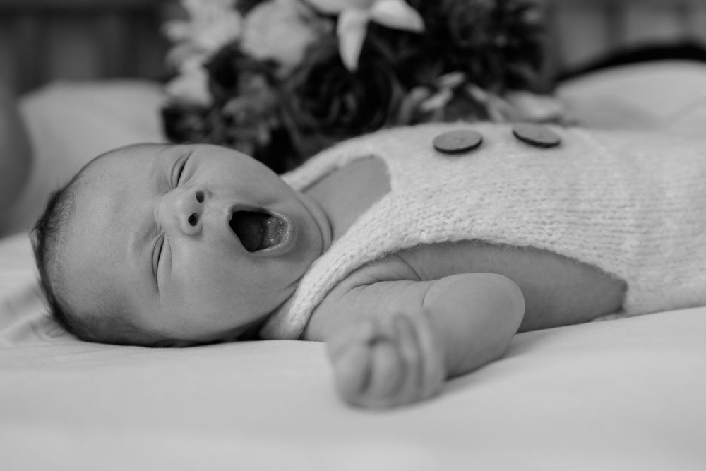 Black and white photo of newborn with a big yawn. Lifestyle Newborn photoshoot
