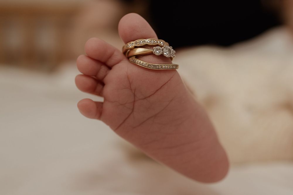 Close up macro of newborn foot with creases and a wedding ring on her toe