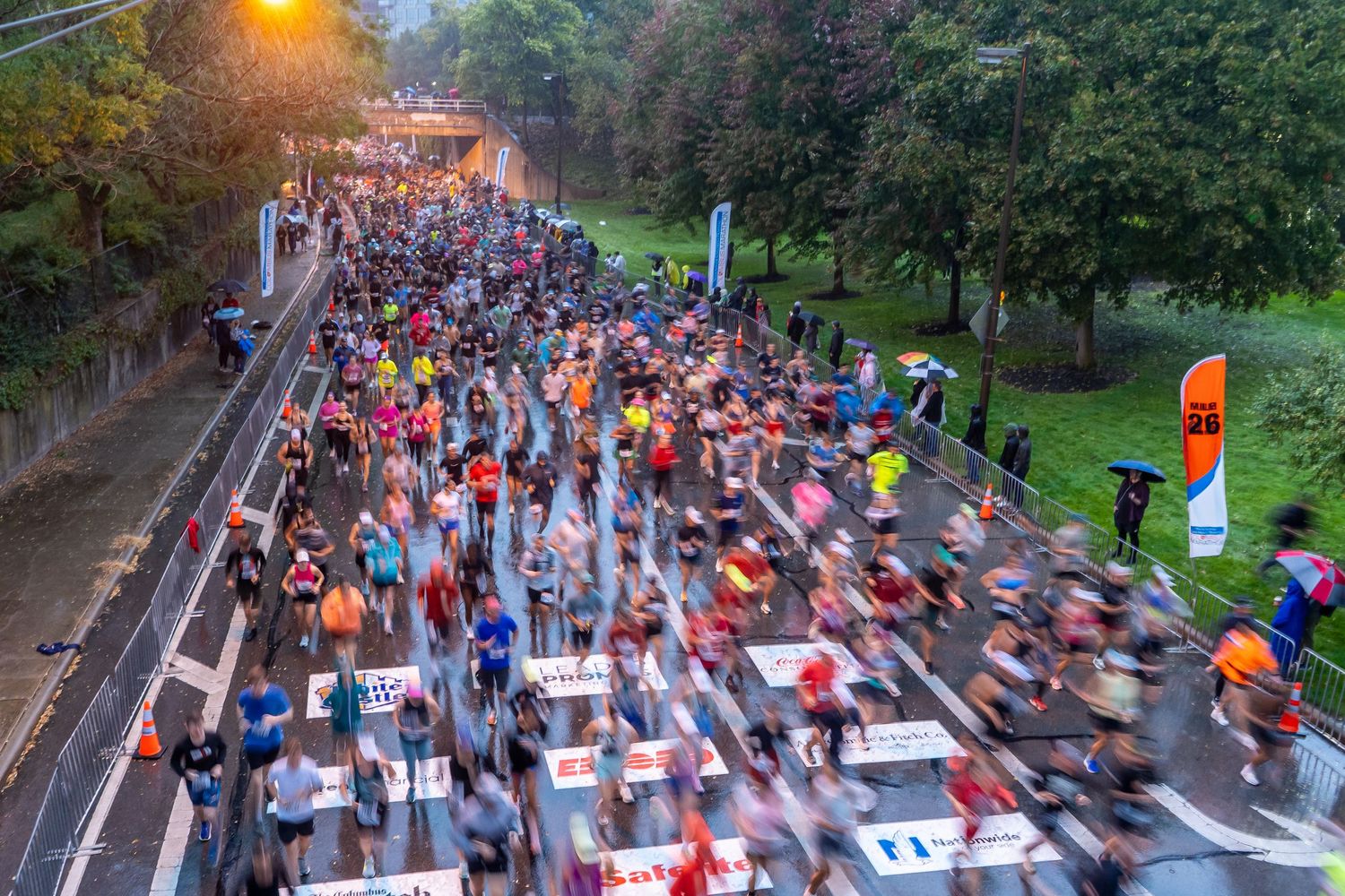 Aerial view of marathon runners at sunrise crossing a bridge during a large racing event.