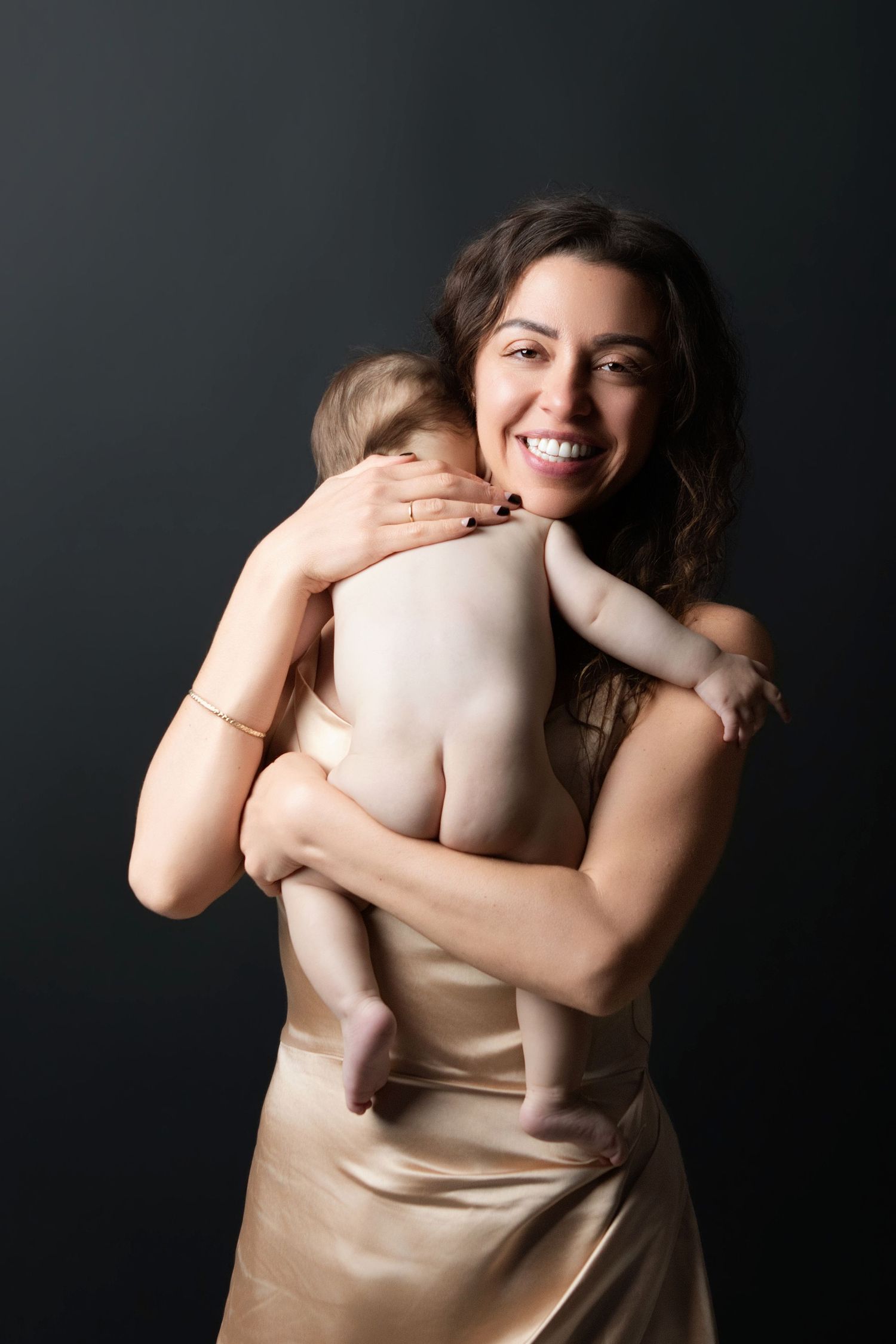 Pregnant woman in elegant red ruffled off-shoulder gown poses gracefully against black background.