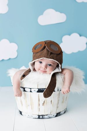 6 month old baby photos, smiling infant wearing a vintage pilot hat and goggles sitting in a rustic white wooden bucket.