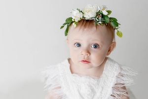 Baby girl in white lace dress and floral crown with blue eyes on white background by Menifee California photographer.