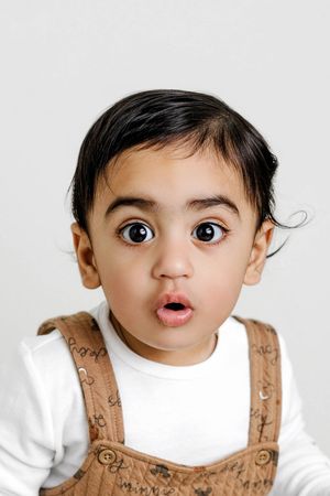 Baby boy's 1st birthday portrait with cute surprised expression.