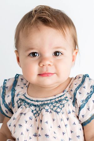 Portrait of cute baby girl with brown eyes in floral smocked dress.