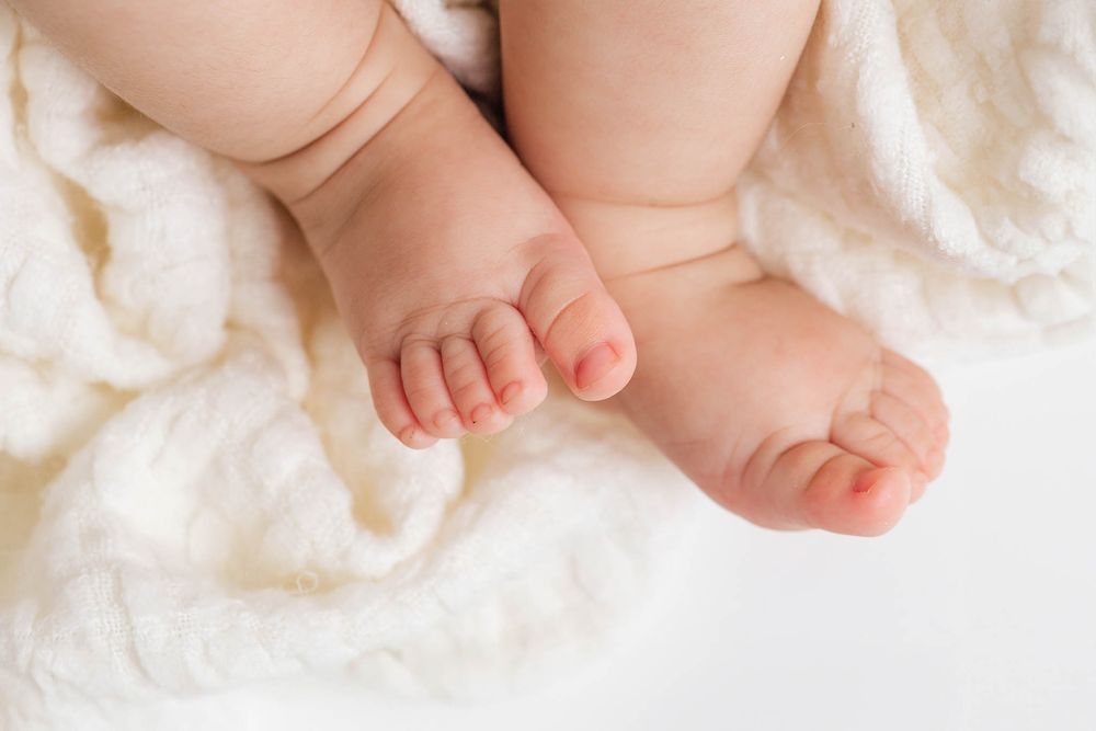 Menifee photographer close-up of newborn baby feet resting on soft white fluffy blanket.