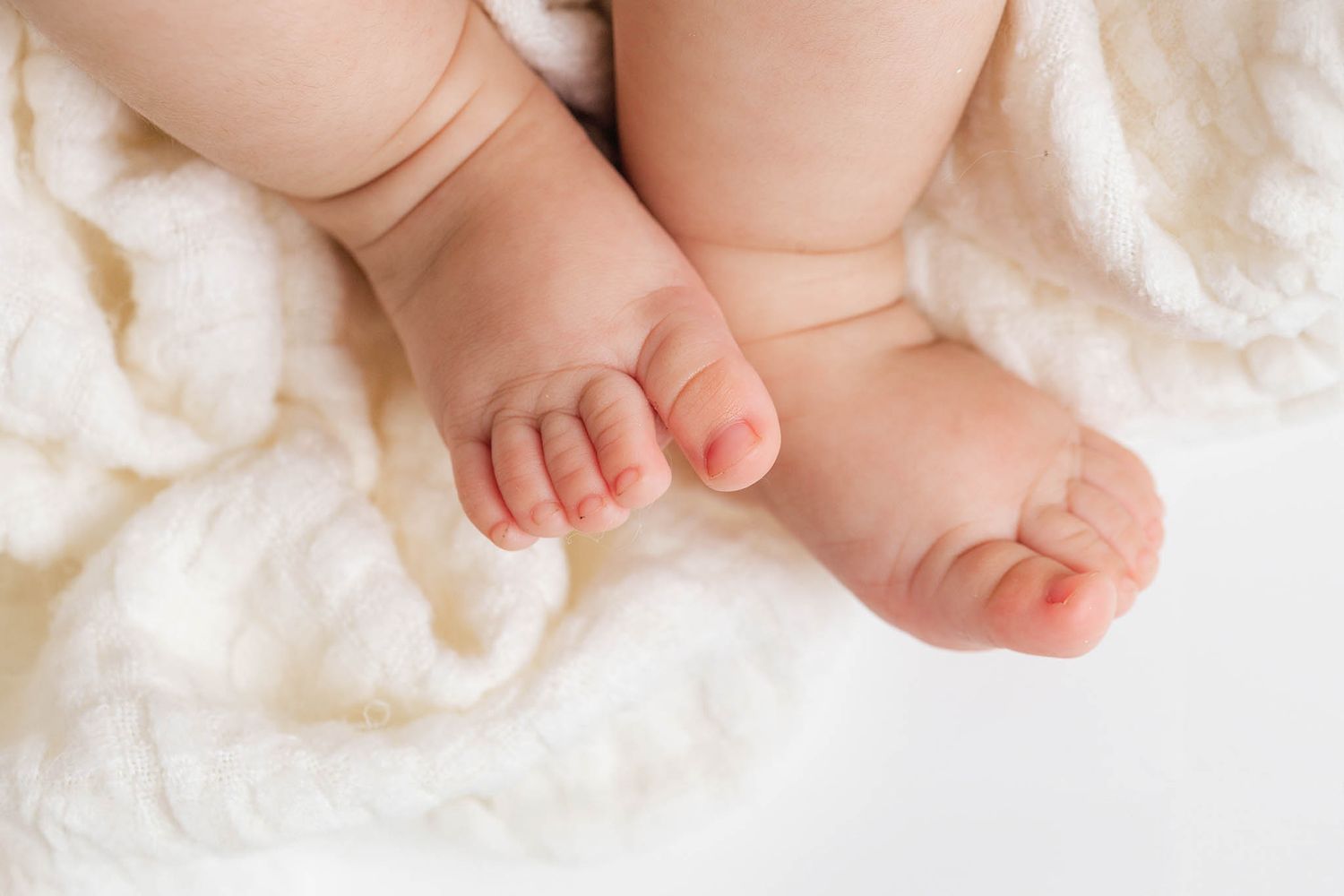 Menifee photographer close-up of newborn baby feet resting on soft white fluffy blanket.