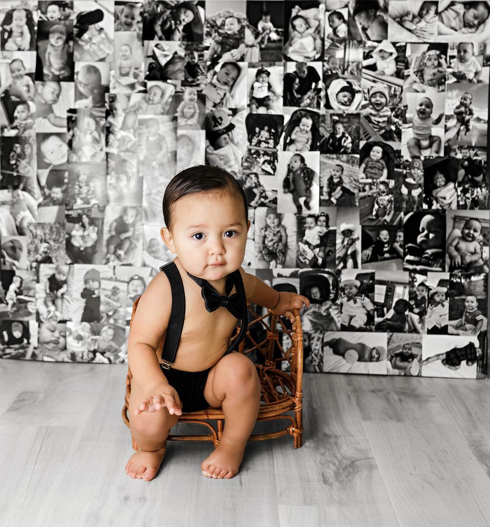Baby boy in 1st birthday outfit sitting in front of photo collage wall celebrating first year of life by SoCal professional photographer.