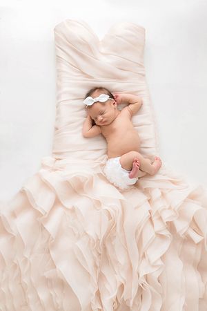 Wildomar professional newborn photographer picture of newborn baby sleeping on a blush pink ruffled wedding dress on white background.