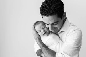 Black and white portrait of dad holding newborn son by affordable newborn photographer in Temecula.