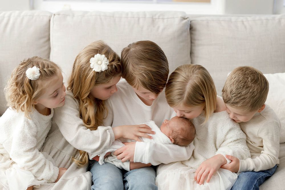 Lifestyle newborn and family photographer in Temecula: Siblings holding their newborn baby brother.