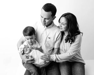 Newborn and family photographer in Menifee: Black and white family portrait of parents and toddler  holding their new baby.