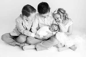 Newborn and family photographer in Menifee: Black and white photo of siblings holding newborn baby sister.