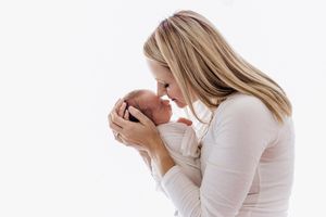 Professional newborn and family photographer in Menifee: Mom and her newborn baby boy against a white backdrop.