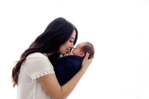 Timeless newborn photographer in Southern California: mom holding her newborn baby boy against bright white background.
