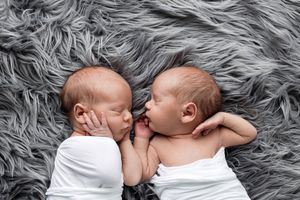 Professional twin newborns photographer in Menifee area: idental newborn twins sleeping peacefully side by side.