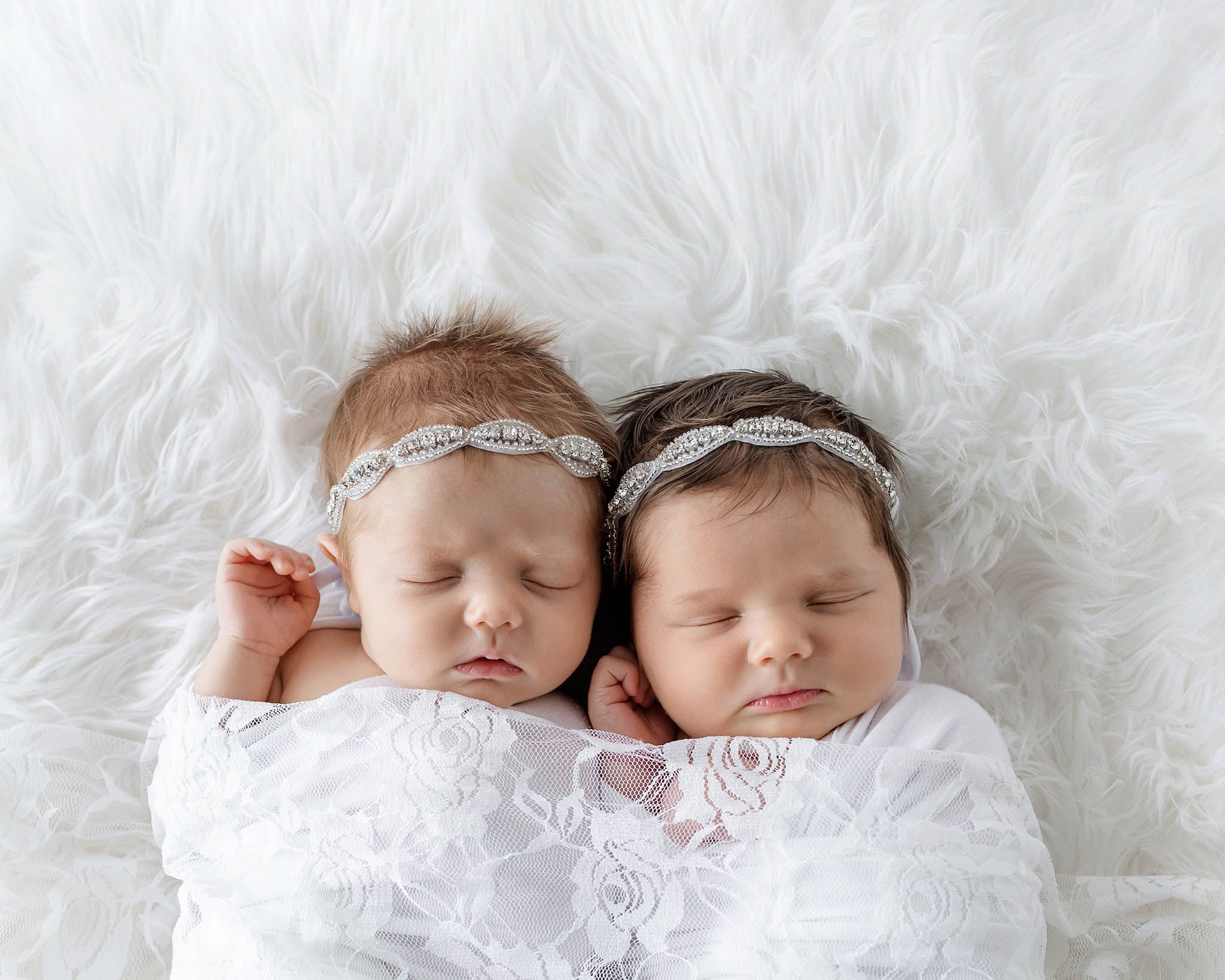 Newborn twins photographer in Menifee: Adorable twin baby girls swaddled in white lace with matching rhinestone headbands.
