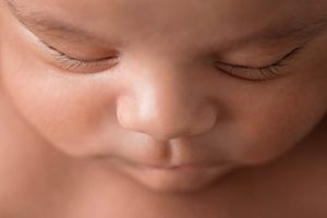 Extreme close-up macro portrait of a peaceful sleeping newborn baby face with delicate features.