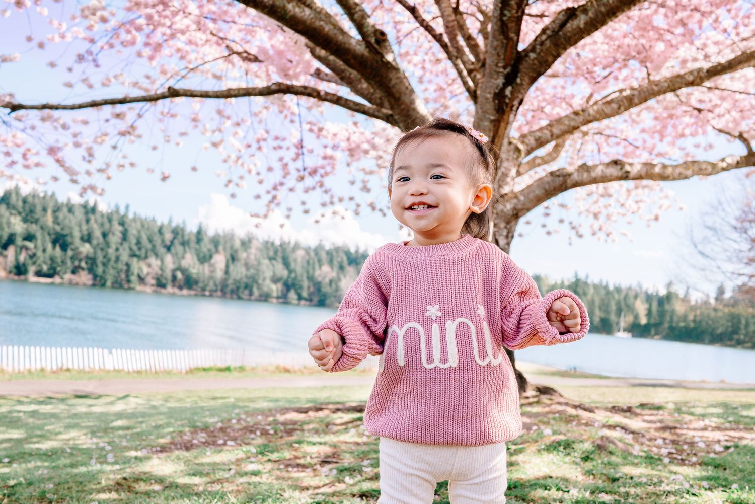 Baby standing under cherry blossoms in Seattle beside Lake Washington, near Seward Park.