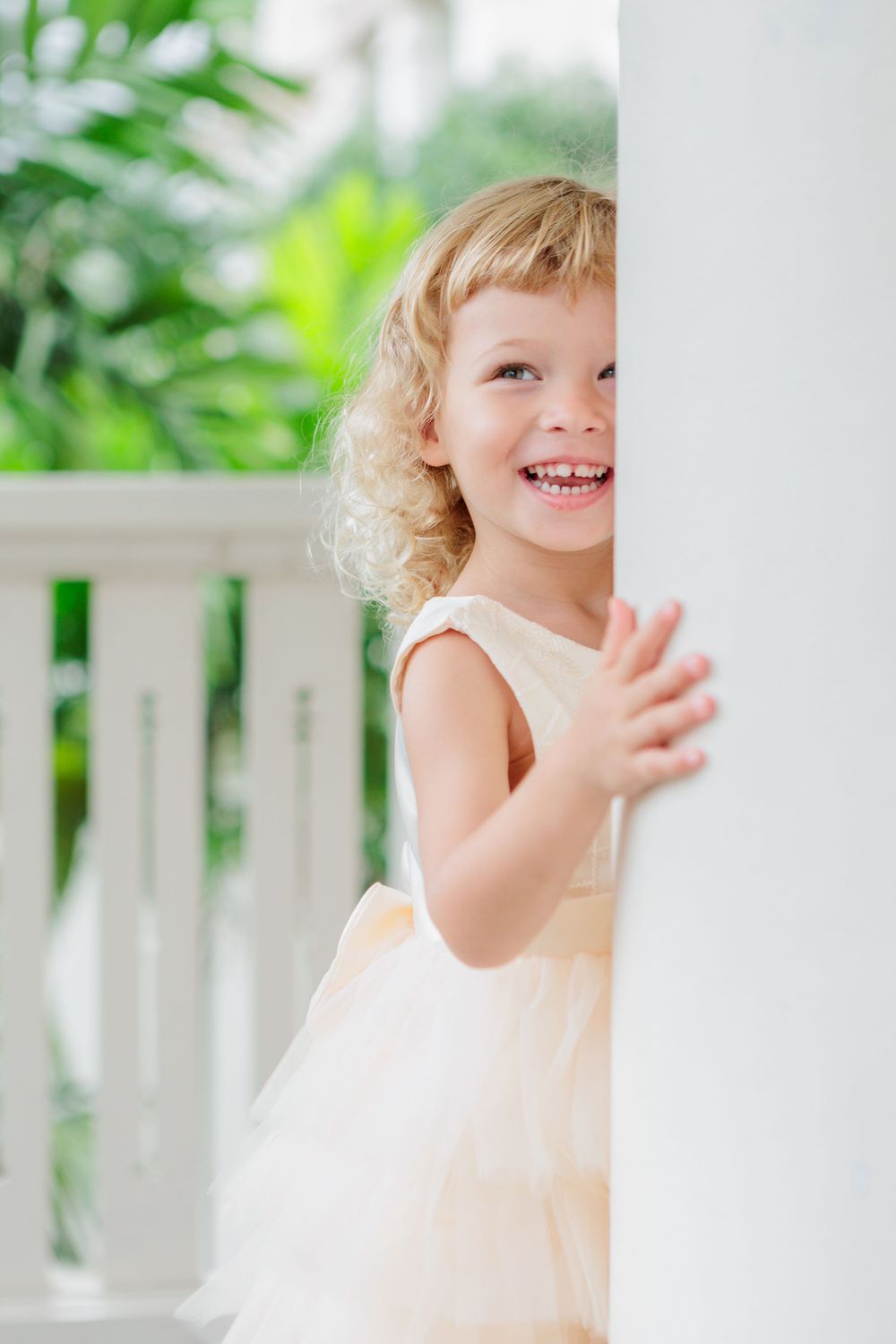 laughing blonde curly child in white colonial building