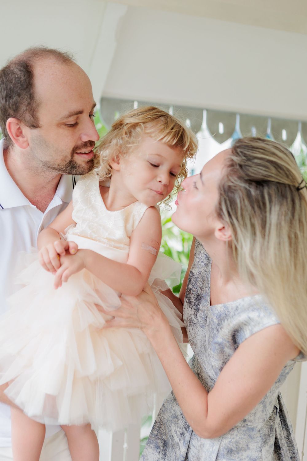 A Relaxed Family Photoshoot in a Singapore Condo. Russian caucasian couple with a blond child in light wooden balcony with green foliage