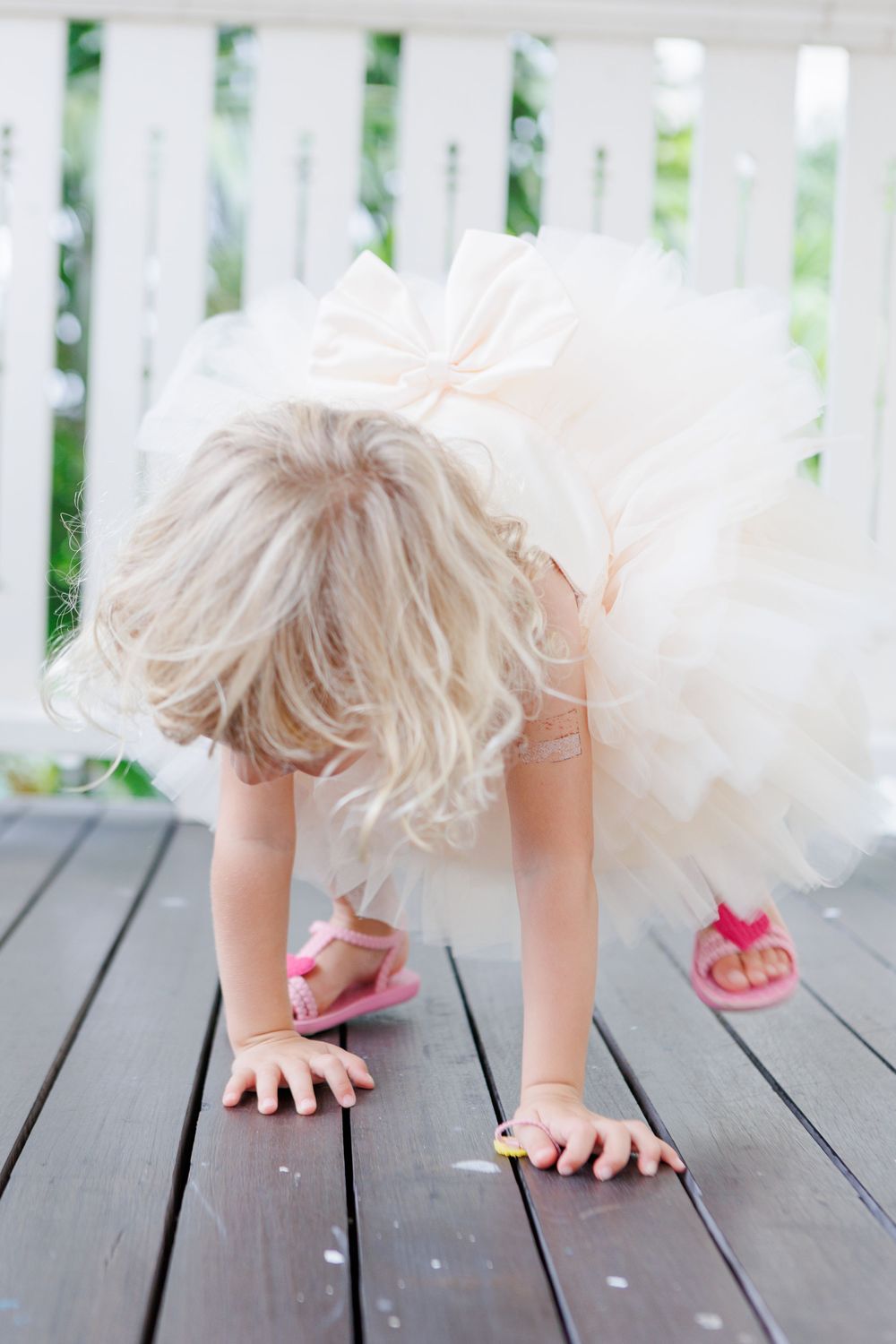 laughing blonde curly child in white dress and colonial building. Playing on wooden floor