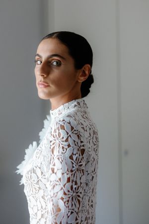 Close-up portrait of bride in intricate white lace high-neck wedding gown with elegant updo.