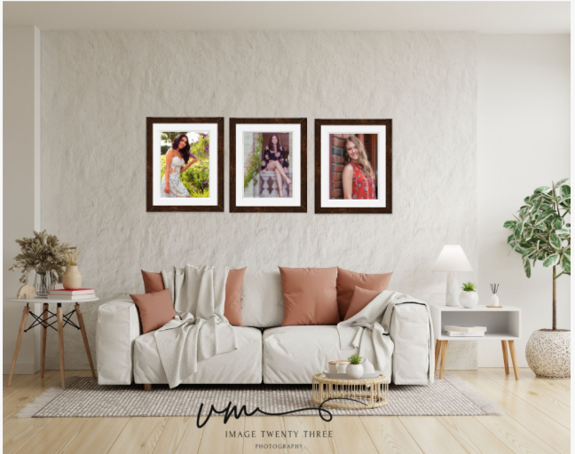 Three framed portrait photos of women displayed above a white sofa in a bright modern living room by Image Twenty Three.