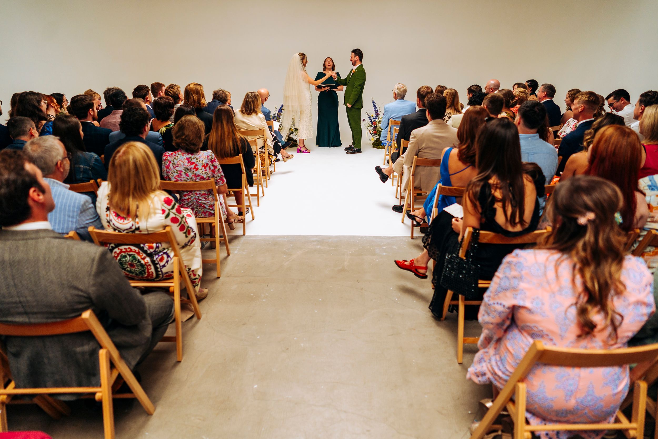 Couple stands at altar before seated guests in a modern wedding venue.
