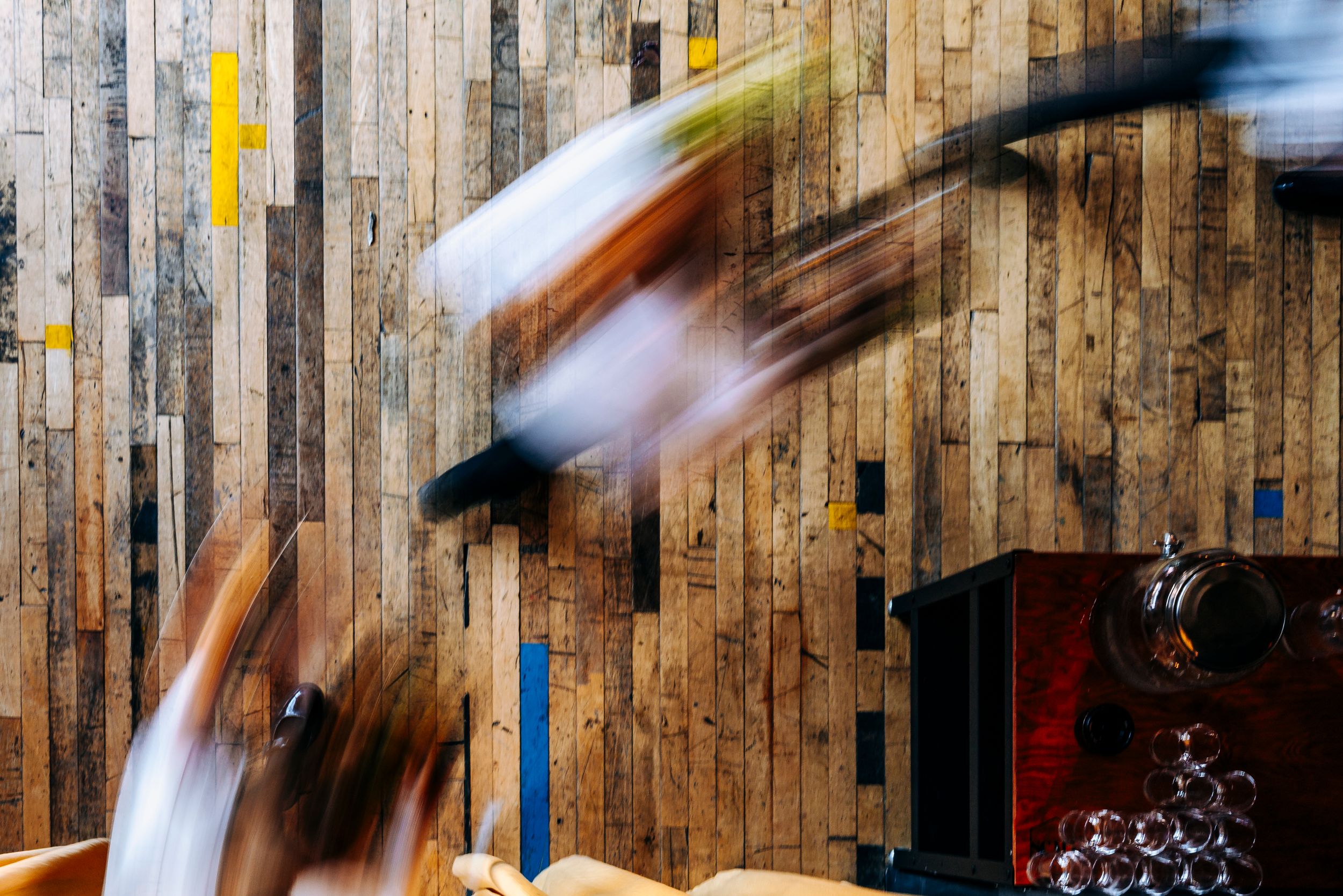 Motion blur artistic photo of musicians performing against a colorful reclaimed wood panel wall at a wedding.